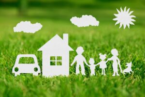 Paper cut of family with house and car on green grass representing your dream home